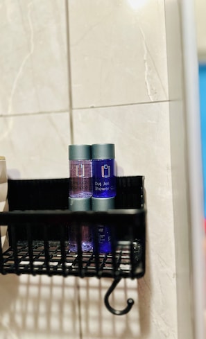 Uno scaffale in bagno con due flaconi di shampoo e una bottiglia di bagnoschiuma.