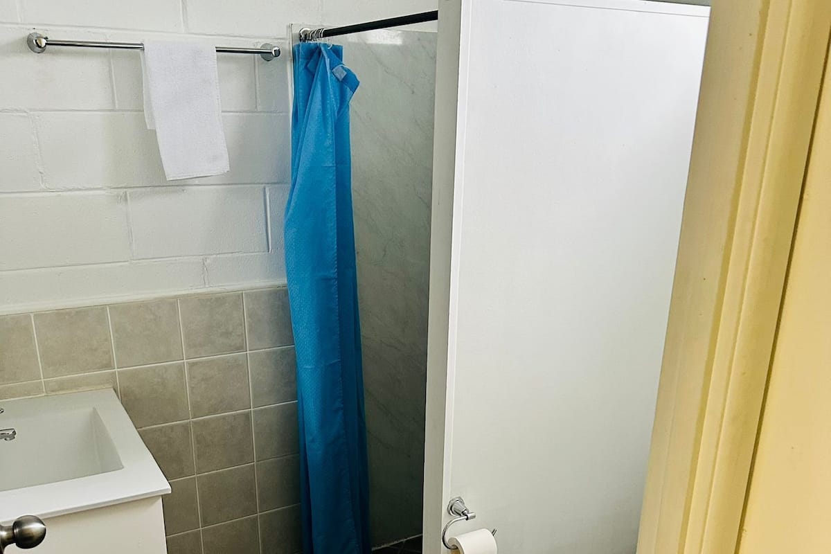 Een compacte badkamer met een wit wastafel, toilet en douchehoek.