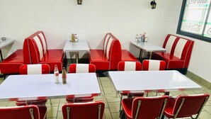 A diner with red booths and white tables, equipped with chairs and small tables.