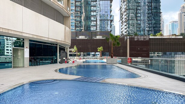 Une piscine sur le toit, au design moderne, entourée d’immeubles de grande hauteur.