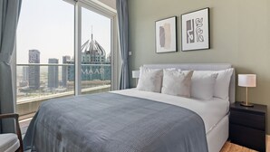 Une chambre d’hôtel avec un grand lit, une table de chevet, une lampe et une vue sur le paysage urbain, visible à travers une grande fenêtre.