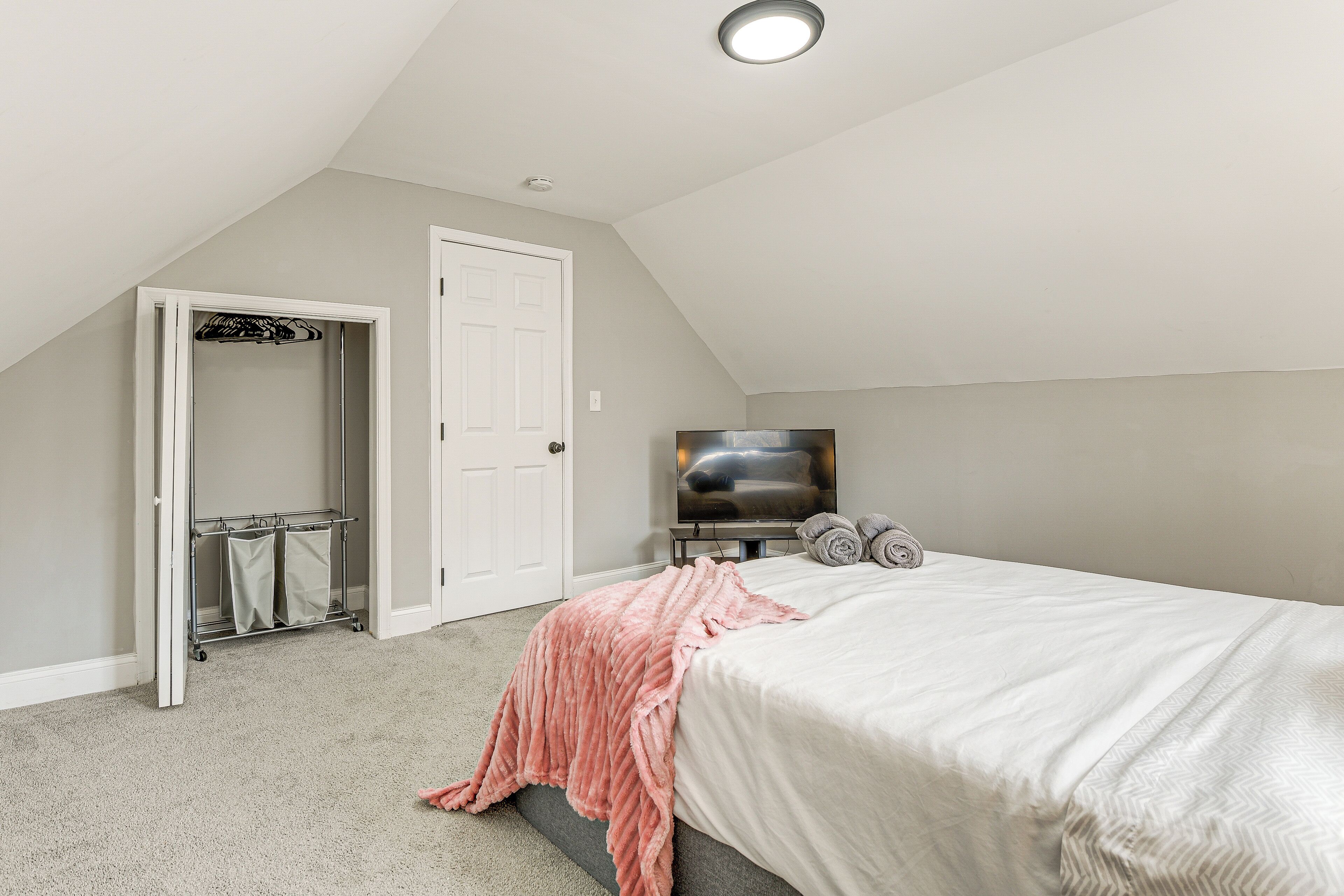Un dormitorio con cama, televisor, armario y puerta.