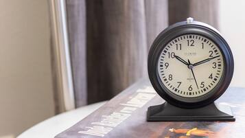 Un reloj de pared redondo con marco negro sobre una pequeña mesa blanca.