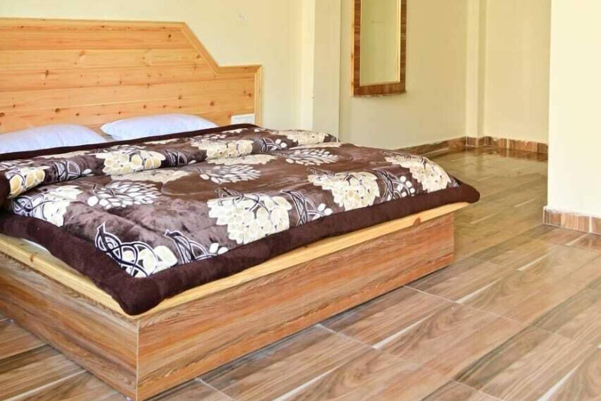 Ein Schlafzimmer mit einem hölzernen Bett, einem Spiegel an der Wand und einer gemusterten Bettdecke.