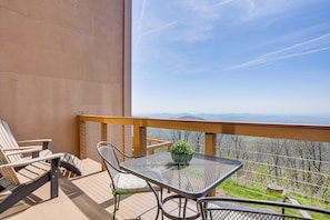 Ein Balkon mit Tisch und Stühlen, einem Blumentopf und Blick auf die Berge.