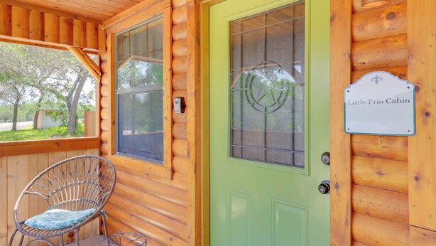 Puuinen mökki, jossa on vihreä ovi, rottinkituoli ja kyltti, jossa lukee: ”Little Frio Cabin”.