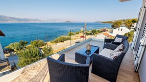 A balcony with wicker furniture, a table, and a view of the sea and distant mountains. - Vila Perla Slatine - Charming 4-bedroom villa with Pool (Slatine)