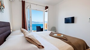 A hotel room with a bed, a television, a view of the sea, and a window with curtains. - Vila Perla Slatine - Charming 4-bedroom villa with Pool (Slatine)