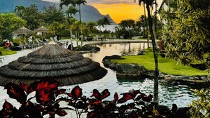 Un resort con piscina, palmeras y una montaña al fondo.