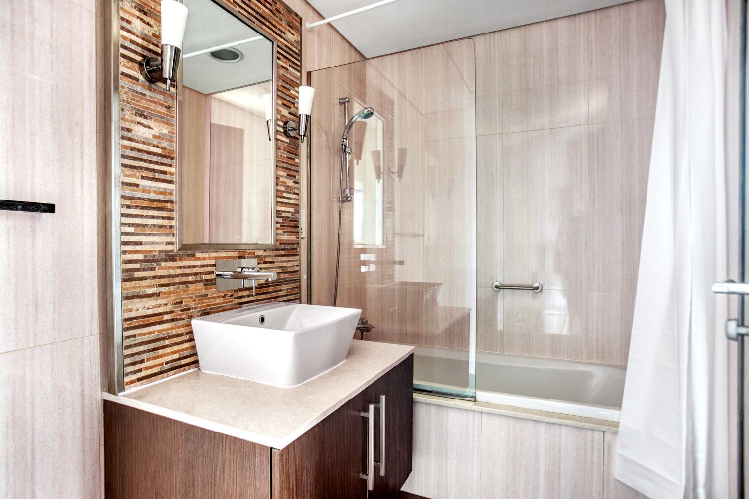 Un baño moderno con una bañera independiente, cabina de ducha de vidrio y una pared decorativa de madera.