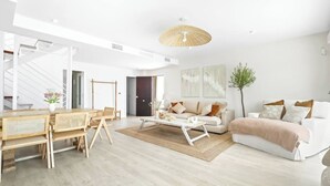 Ein geräumiges Wohnzimmer mit einem Holzesstzimmer, einem weißen Sofa und einem großen Fenster.