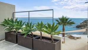 Ein Balkon mit Topfpflanzen, Meerblick und einem Liegestuhl.