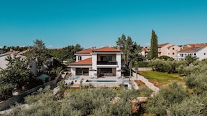 Una casa de dos pisos con balcón, piscina y jardín.
