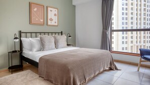 A bedroom with a bed, two bedside lamps, a window with curtains, and a city view. - Blueground | Jumeirah Beach Residence, pool, nr Marina (Dubai)