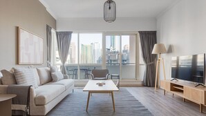Ein modernes Wohnzimmer mit einer Couch, einem Couchtisch, einem Fernseher und einem Balkon mit Vorhängen.