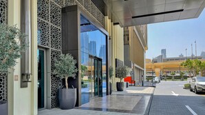 A modern building with large glass windows, potted plants, and a paved sidewalk.