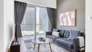 A modern living room with a grey sofa, a round coffee table, and a large window with curtains.