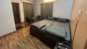 Une chambre à coucher comprenant un lit, un bureau, une chaise, un climatiseur et un ventilateur de plafond.