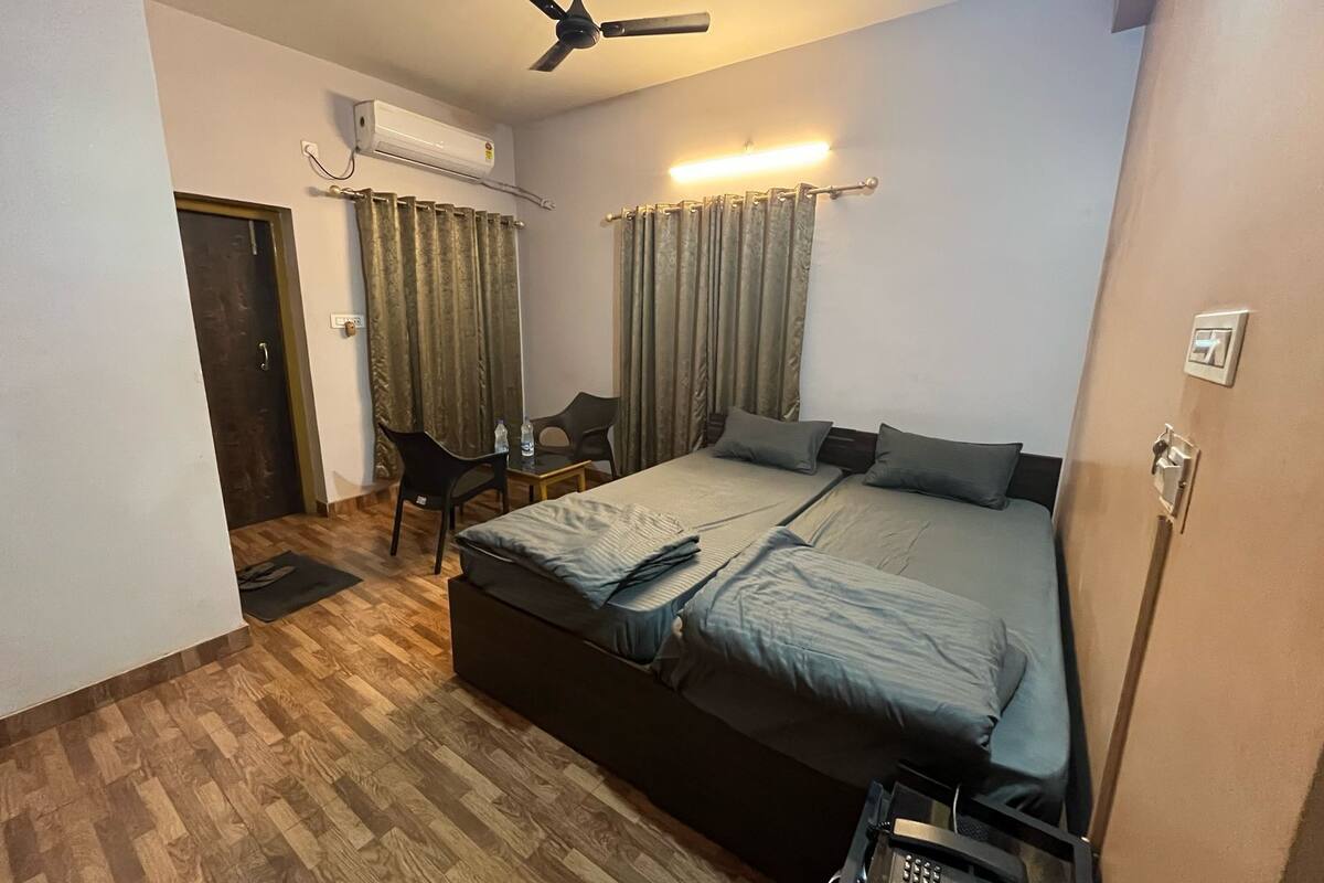 A bedroom with a bed, a desk, a chair, an air conditioner, and a ceiling fan.