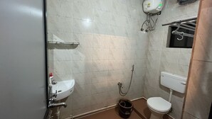 Une petite salle de bain comprenant un lavabo, des toilettes, une douche et un porte-serviettes.