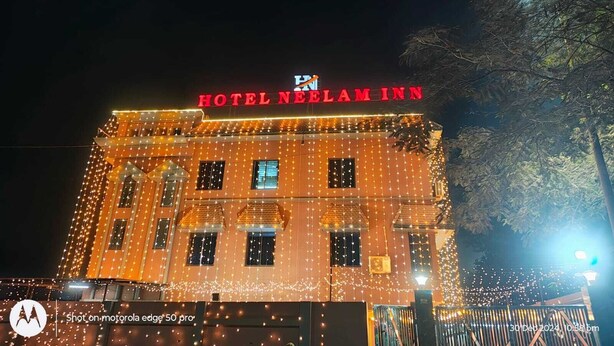 Un bâtiment sur lequel on peut lire l’inscription « HÔTEL NEELAM INN » et qui est décoré de guirlandes lumineuses.