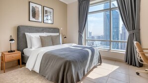 Une chambre d’hôtel moderne avec un grand lit, une table de chevet, une chaise et une vue sur le paysage urbain par la fenêtre.
