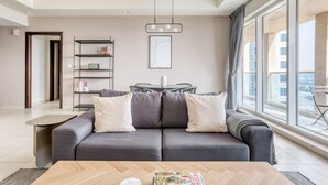 A modern living room with a grey sofa, a wooden coffee table, and a dining area with a small table and chairs.