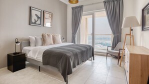 A modern bedroom with a bed, bedside tables, a desk, and a view of the outdoors.