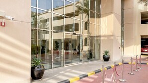 A modern building with large glass windows, a red carpet, and potted plants.
