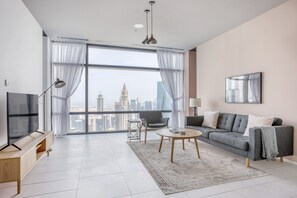 A modern living room with a large window, a sofa, a coffee table, and a TV.