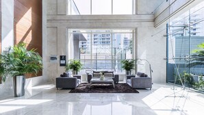 Un vaste espace de vie au design moderne, comprenant une grande fenêtre offrant une vue sur la ville, une table basse centrale et deux canapés.
