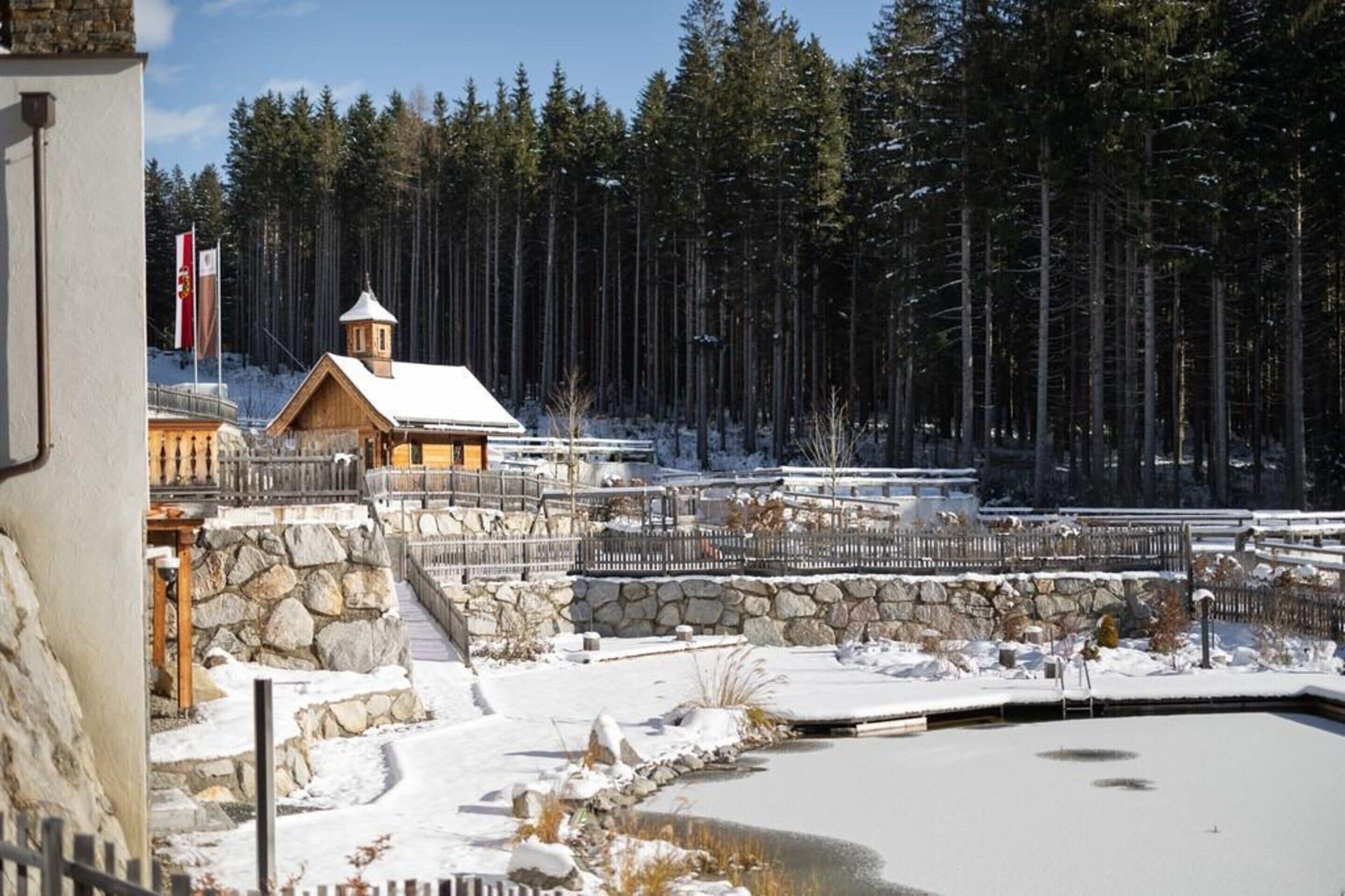A wooden cabin with a stone wall and a snow-covered landscape.