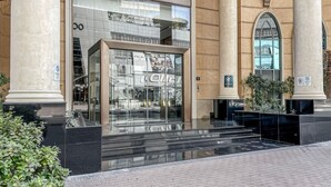 Un bâtiment moderne doté d’une façade en verre, d’une entrée imposante et d’éléments architecturaux classiques, tels que des colonnes et des arches.