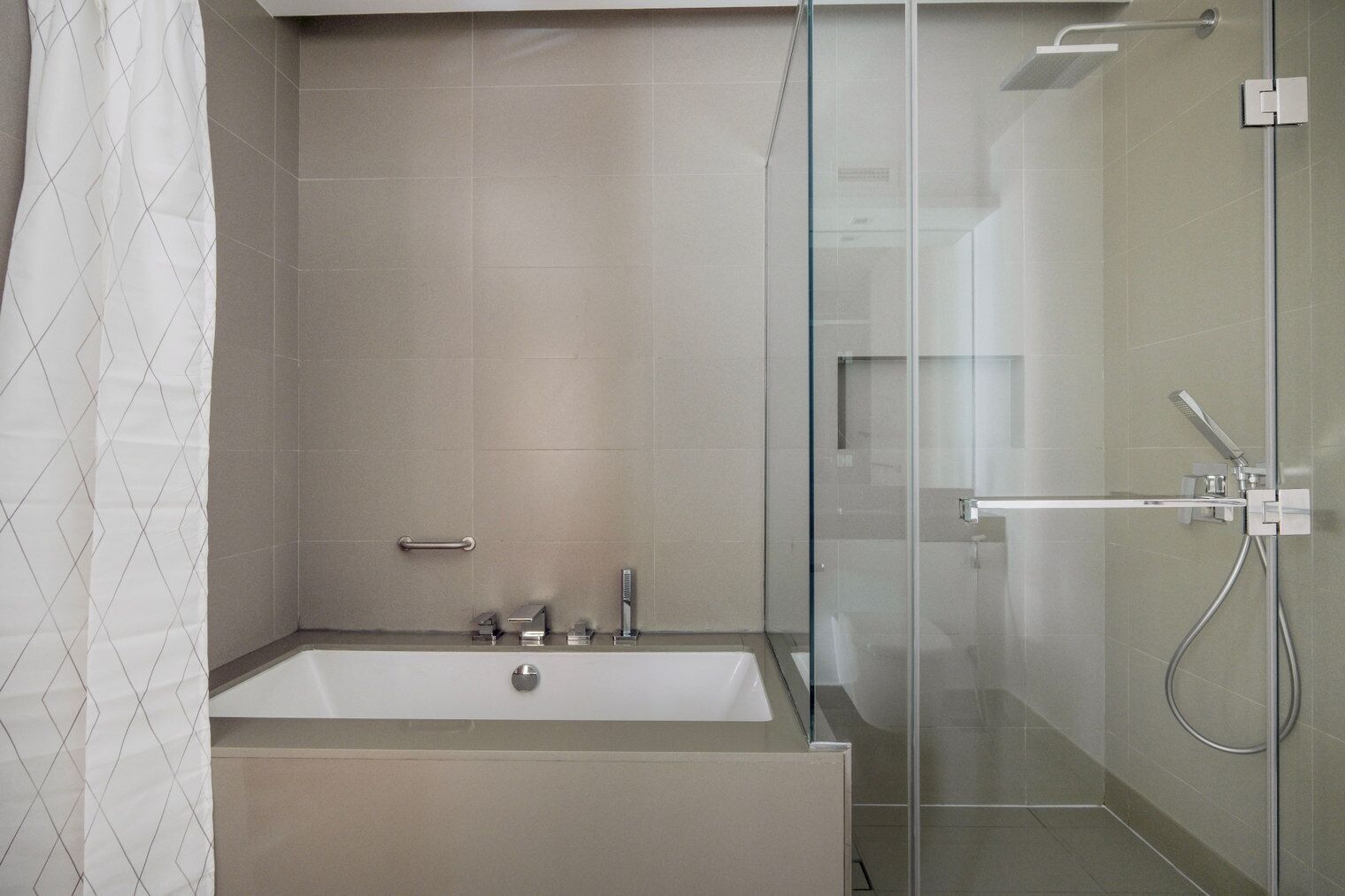 Un baño moderno con ducha de vidrio, bañera independiente y toallero.