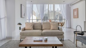Ein modernes Wohnzimmer mit einer Couch, einem Couchtisch und einem Essbereich mit Tisch und Stühlen.