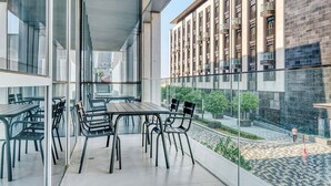 Ein moderner Außenbereich zum Sitzen mit Glastrennwand und Blick auf die Skyline.