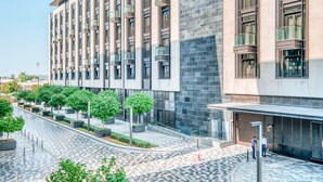 Ein modernes Gebäude mit einer gefliesten Erdgeschossfassade und einer großen Glasfront.