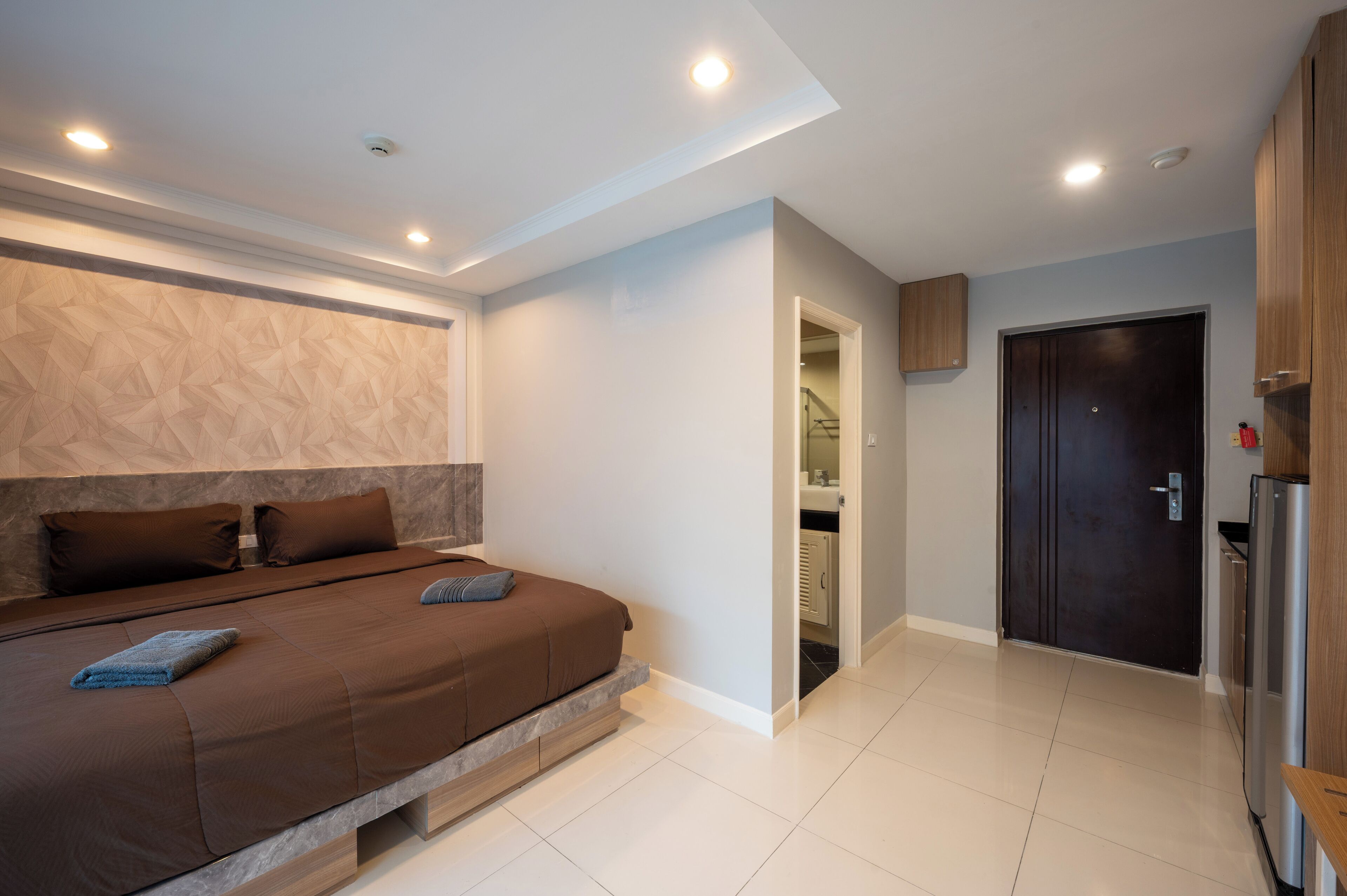 A modern bedroom with a large bed, a built-in bench, and a wardrobe.