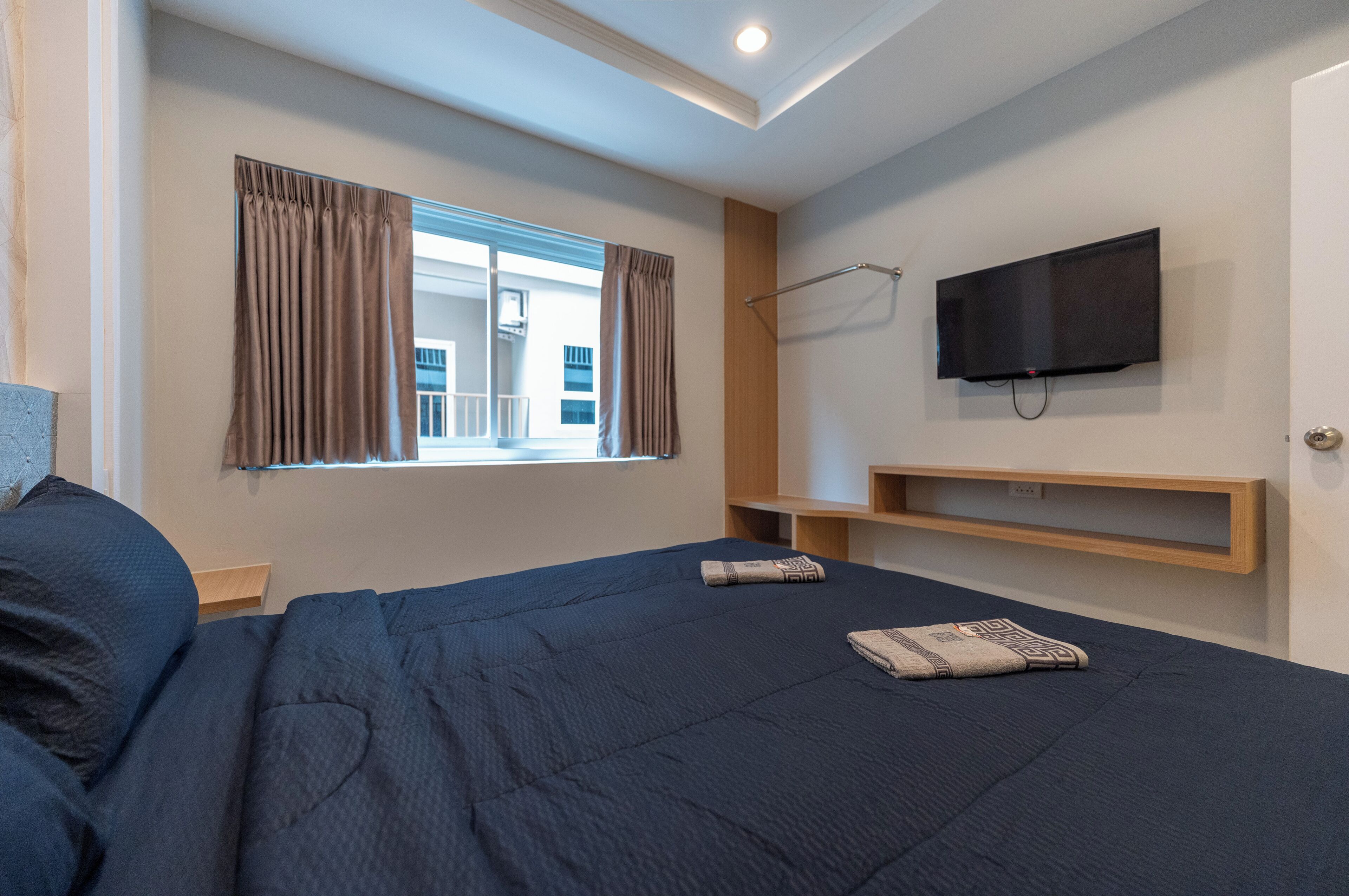 A bedroom with a bed, curtains, a TV, and a window.