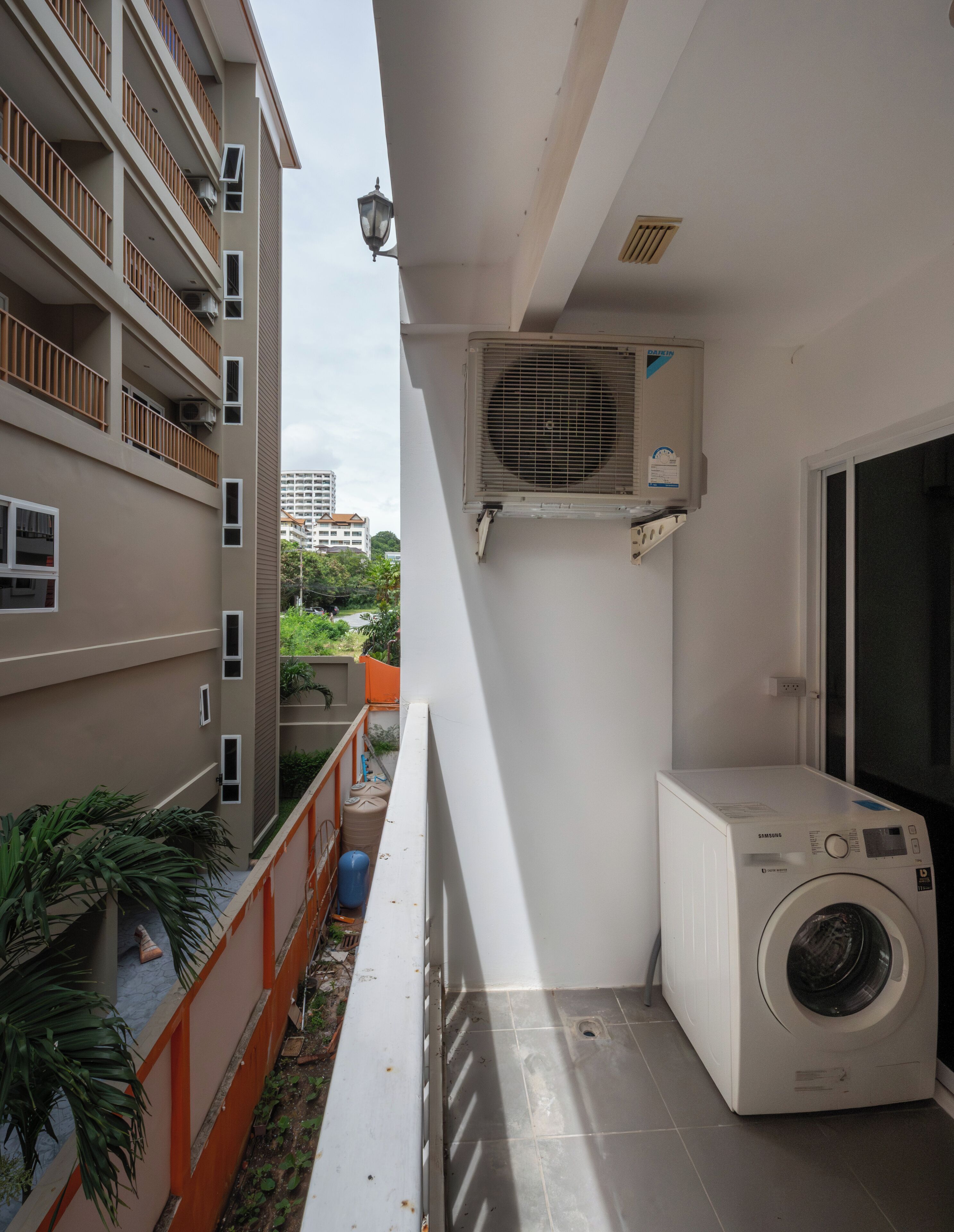 A laundry room with a washing machine, an air conditioning unit, and a window.