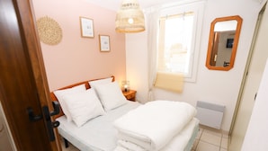 A bedroom with a bed, bedside table, wall decor, and a window with curtains. - St Cyprien beautiful cozy apartment sea view (Saint-Cyprien)