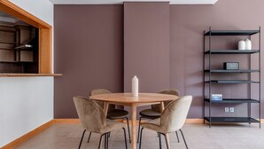 Un comedor moderno con una mesa redonda, cuatro sillas y un centro de mesa con un jarrón blanco.