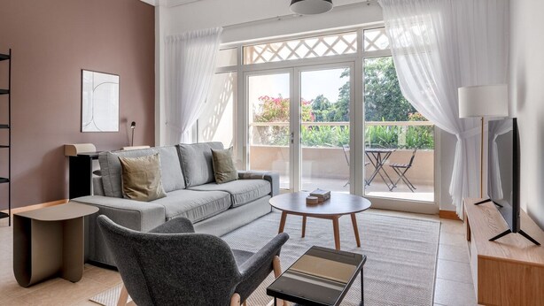 Una sala de estar moderna con un sofá gris, una mesita redonda y un mueble para la televisión.