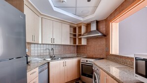 Una cocina moderna con refrigerador de acero inoxidable, horno integrado, lavadora y encimeras de granito.