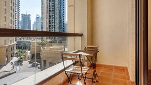 Ein Balkon mit Tisch und Stühlen, Blick auf hohe Gebäude und ein Fliesenboden.