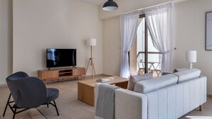 Ein modernes Wohnzimmer mit Flachbildfernseher, einer Couch, einem Sessel und einem Couchtisch.