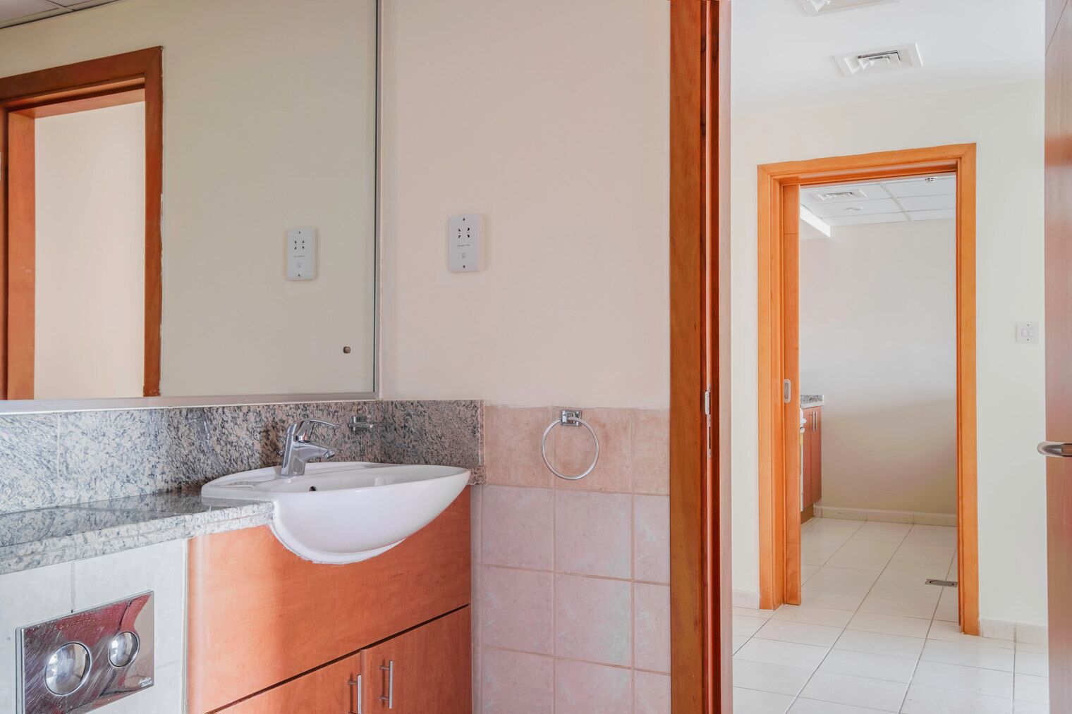 A bathroom with a sink, mirror, and wooden door leading to another room.