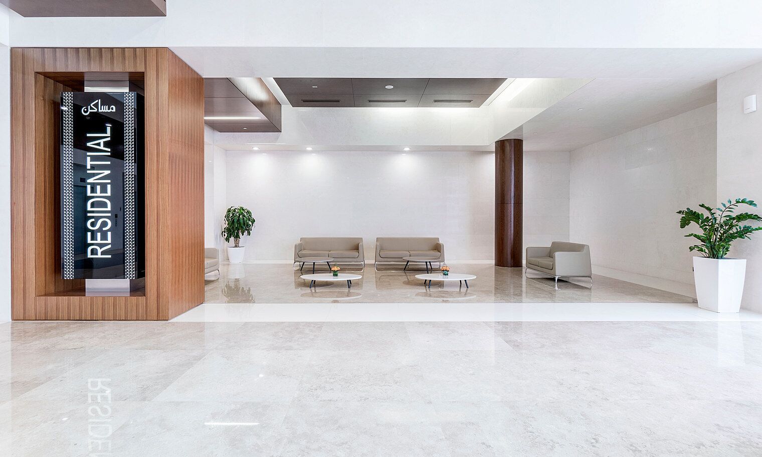 A modern, spacious lobby with a reception desk, two sofas, and a coffee table.