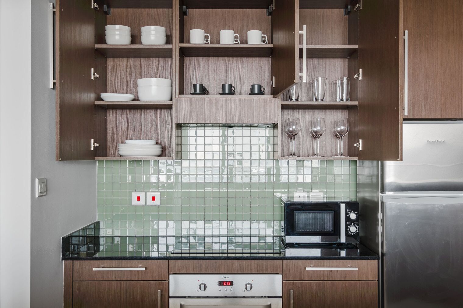 Una cocina moderna con armarios de madera, un microondas, una estufa y un salpicadero de azulejos.