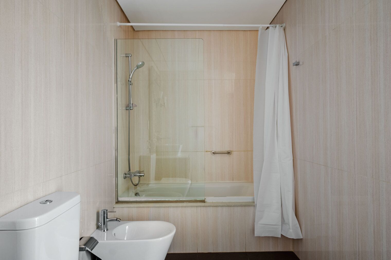 Un baño moderno con ducha de vidrio, lavamanos blanco y retrete.